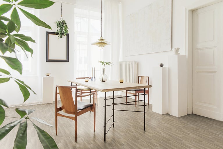 Světlá jídelna s dřevěnou podlahou, jídelním stolem a židlemi.