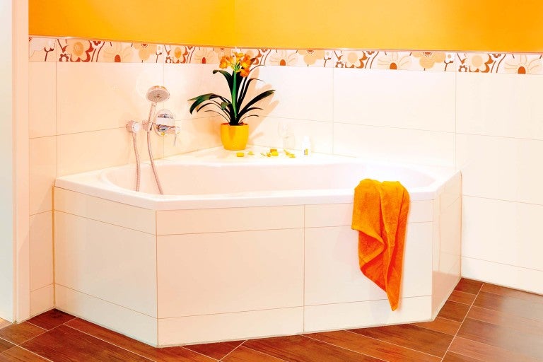 Rohová vana v koupelně s obklady a dekorací