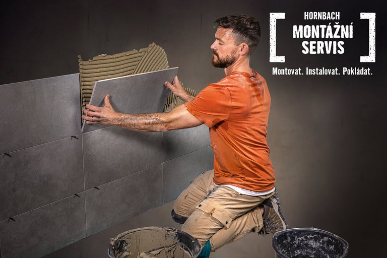 Řemeslník pokládá obklady na zeď. Montážní servis Hornbach.
