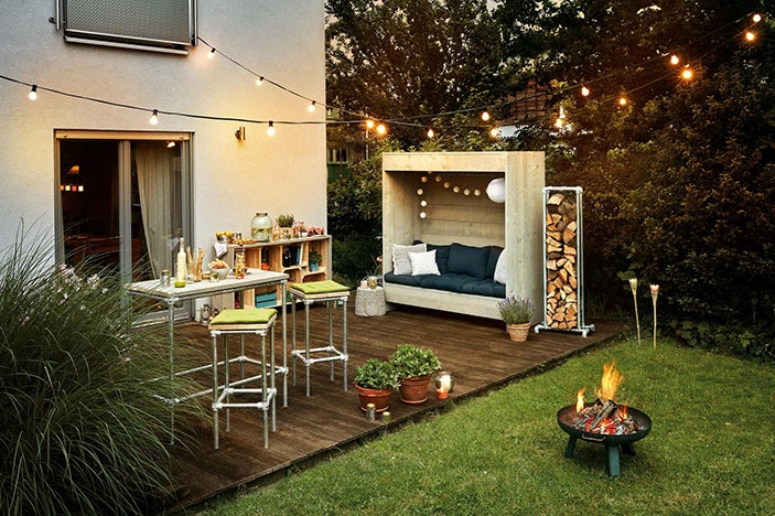 Terasa s vysokým stolem, barovými stoličkami, posezením, ohništěm a světelným řetězem pro příjemné chvíle venku