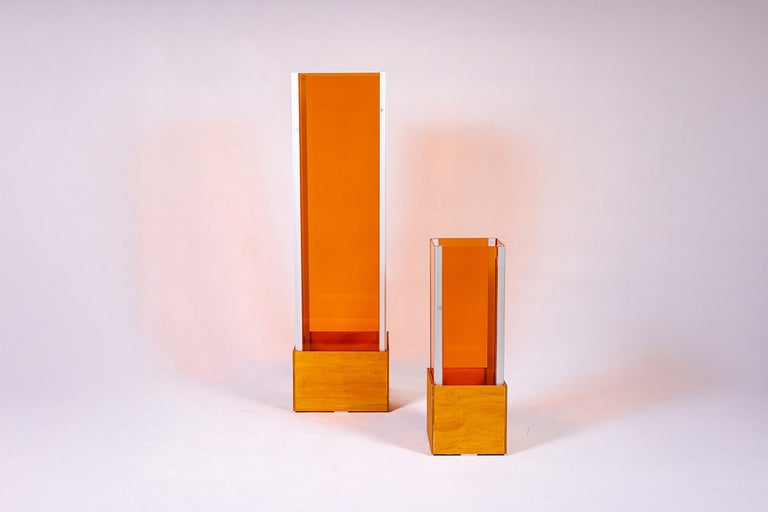 Dvě oranžové vázy z plexiskla s dřevěnou základnou