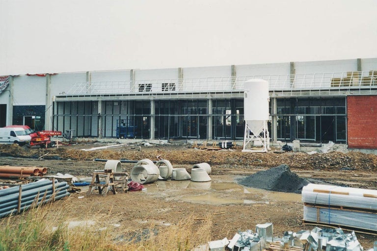 Staveniště se stavebními materiály a trubkami před budovou v hrubém stavu