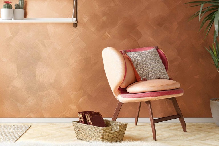 Dekorativní nástěnná dekorace s křeslem, polštářem a košíkem na knihy v obývacím pokoji.