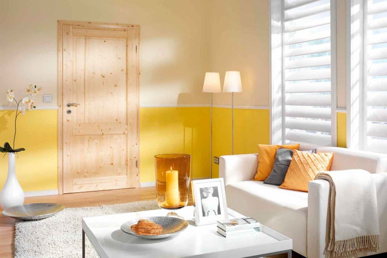 Obývací pokoj s dřevěnými dveřmi, gaučem, žaluziemi a dekorací