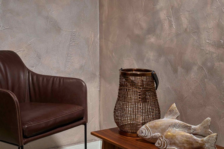 Dekorativní aranžmá s křeslem, lucernou a figurkami ryb na stole.