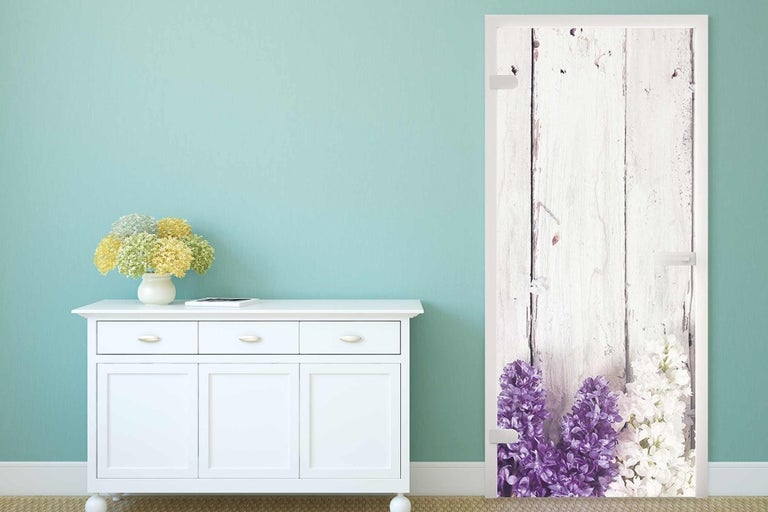 Ozdobné dveře s dřevěnými deskami a květinovým motivem ve světlé místnosti.