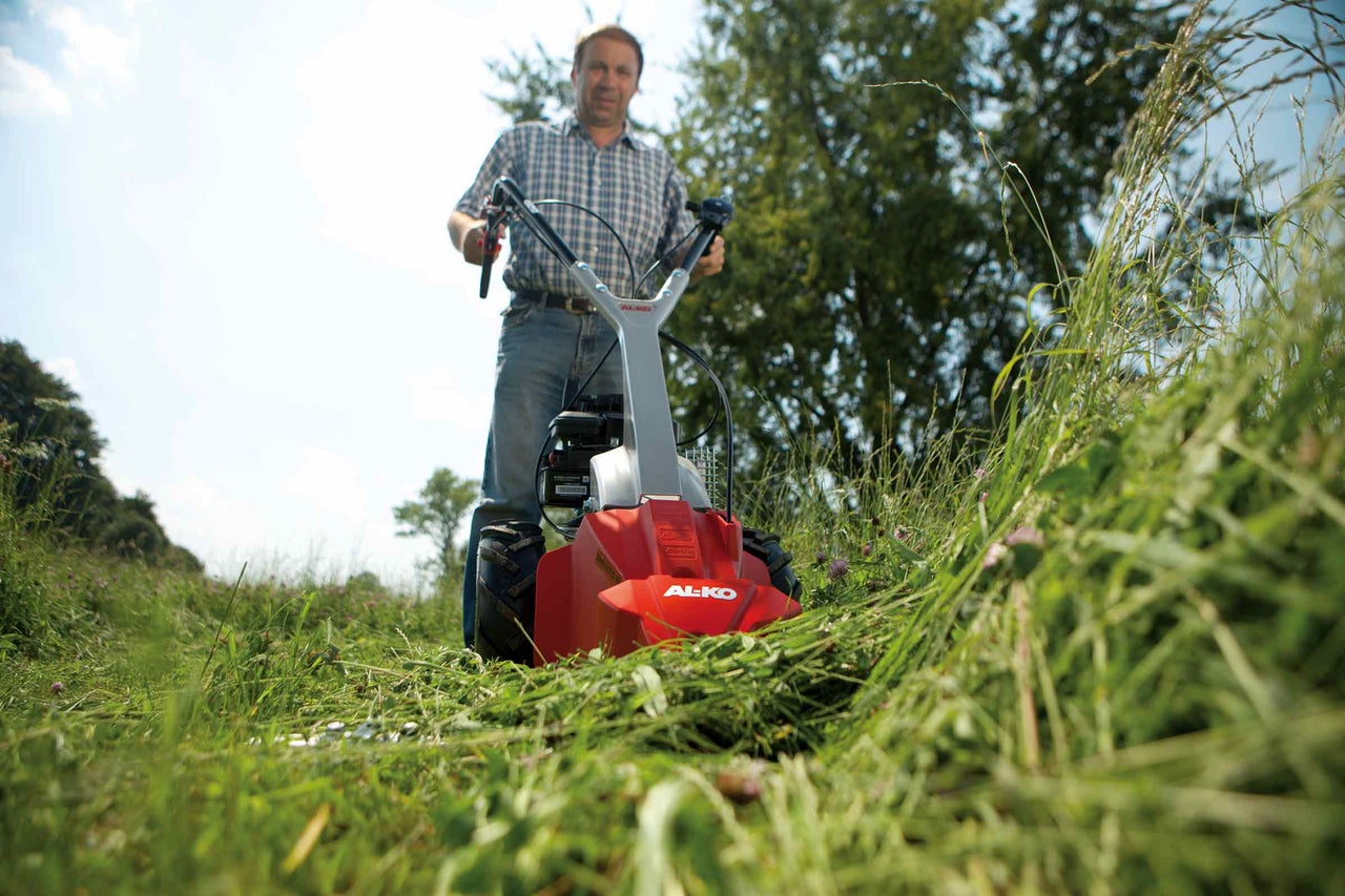 Muž obsluhuje bubnovou sekačku AL-KO při sekání trávy