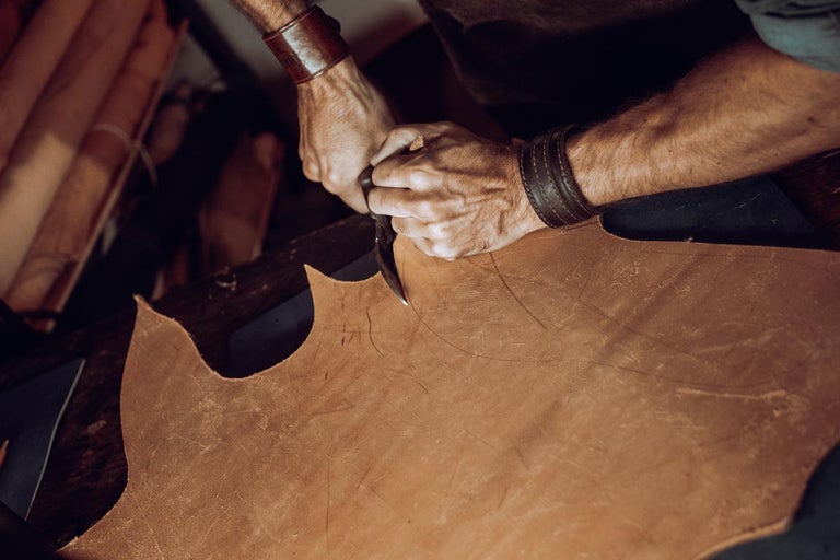 Muž nožem řeže kus kůže.