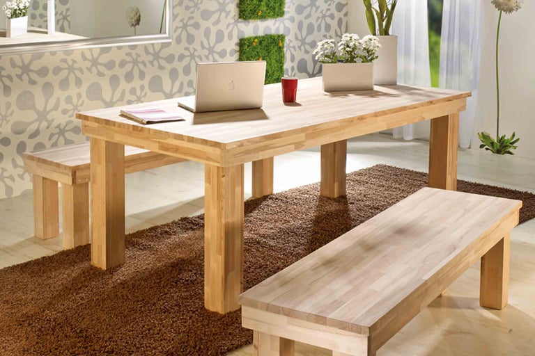 Jídelní stůl se dvěma lavicemi ze světlého dřeva na hnědém koberci