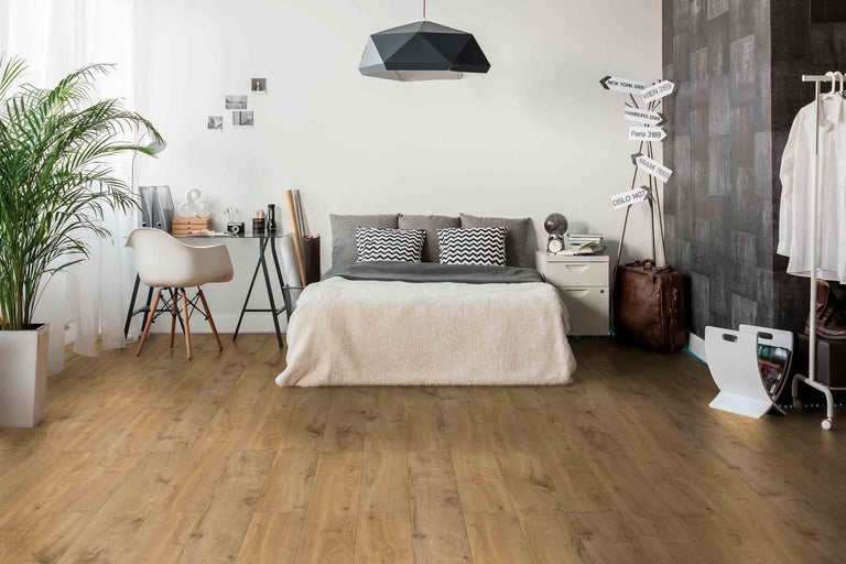 Světlá ložnice s dřevěnou laminátovou podlahou, postelí a psacím stolem.