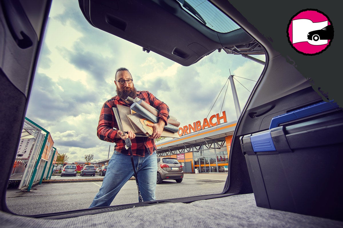 Muž nakládá do kufru auta stavební materiály před prodejnou Hornbach