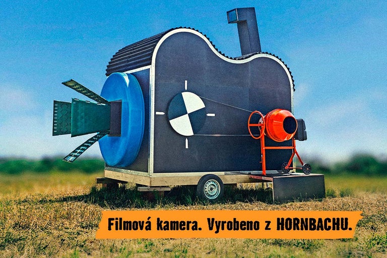 Skulptura ve tvaru filmové kamery vyrobená z různých stavebních materiálů na přívěsu, prezentovaná společností Hornbach.