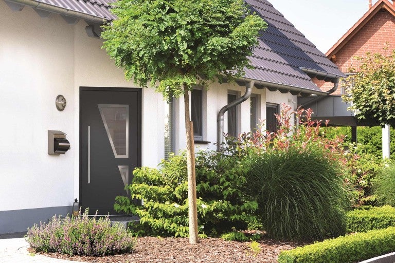 Fasáda domu s vchodovými dveřmi, poštovní schránkou a udržovanou zahradou