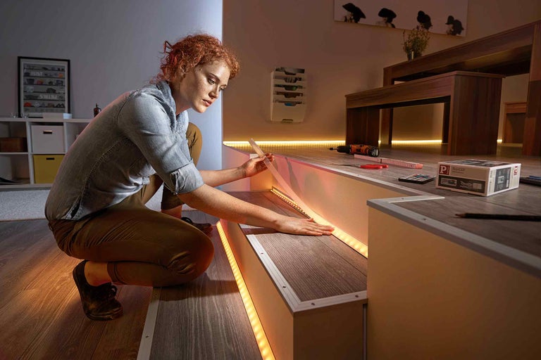 Žena instaluje LED pásky na vnitřní schodiště