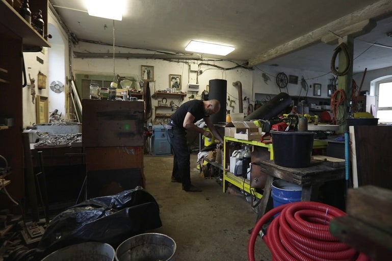 Dílna s nářadím, materiály a osobou pracující na regálu