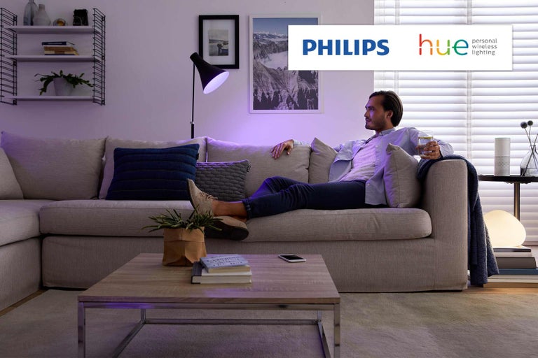 Muž relaxuje na pohovce v obývacím pokoji s osvětlením Philips Hue.