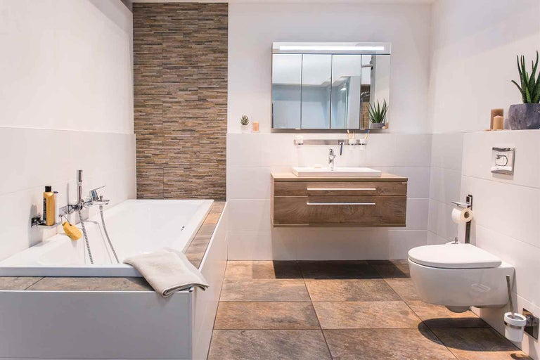 Světlá koupelna s vanou, umyvadlem se skříňkou, zrcadlovou skříňkou a závěsným WC