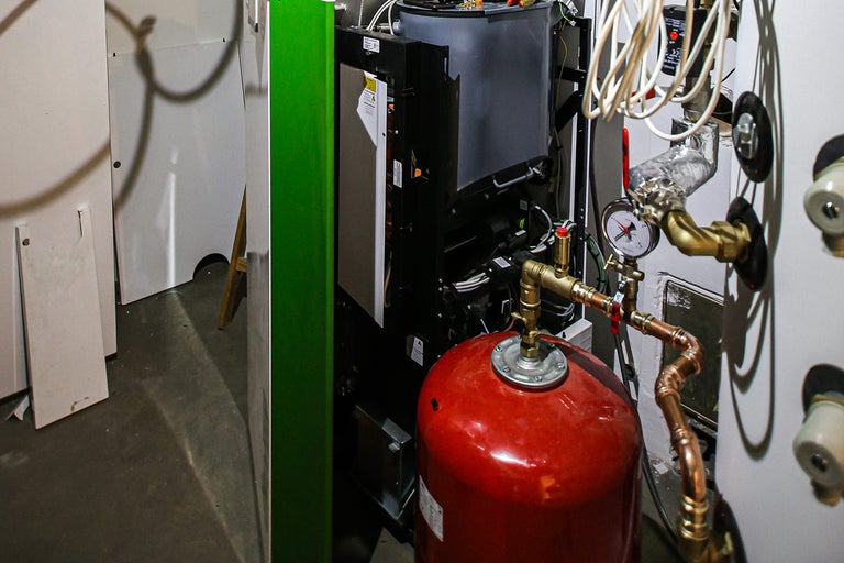 Topný systém s expanzní nádobou, potrubím a manometrem v instalační místnosti
