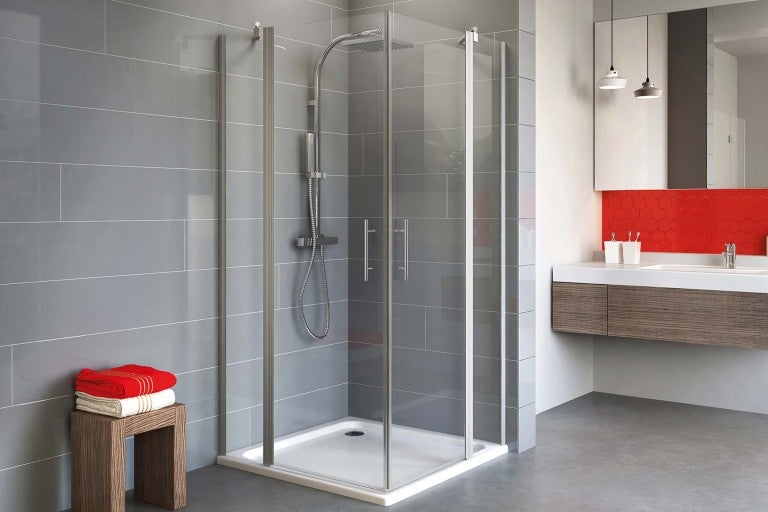 Sprchový kout se sprchovou vaničkou v koupelně s umyvadlovou skříňkou a ručníky