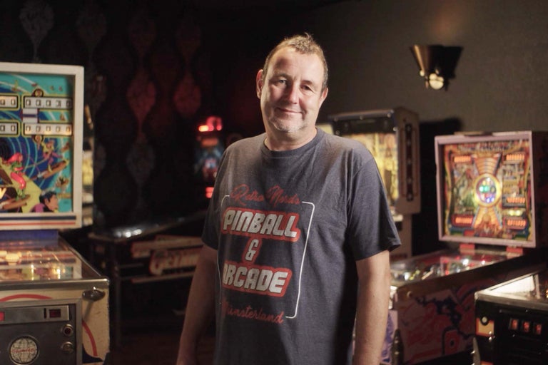 Muž stojí v místnosti s několika hracími automaty.