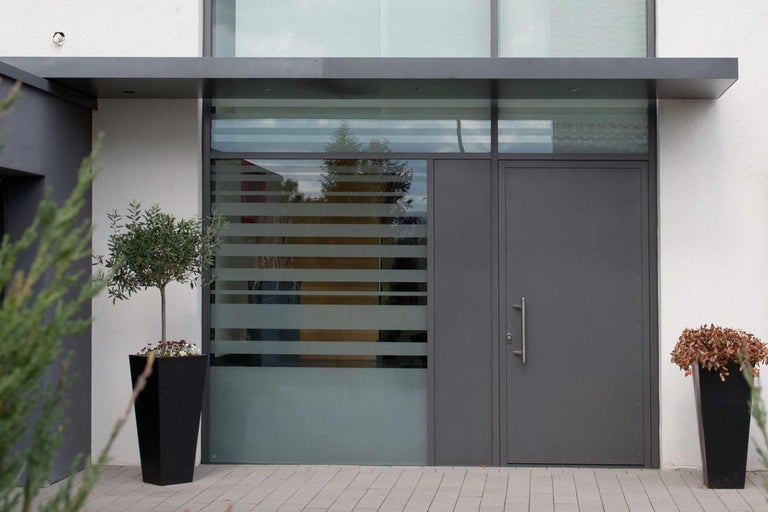 Moderní vchodové dveře s bočním panelem a světlíkem, doplněné květináči