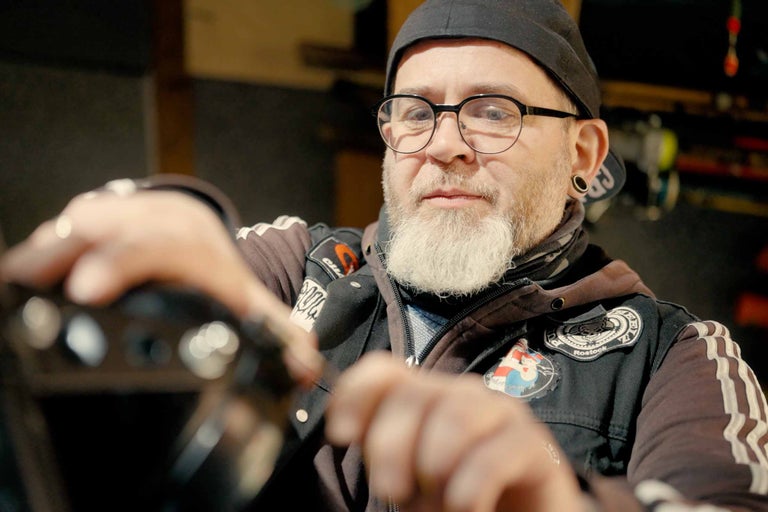 Muž s plnovousem, brýlemi a čepicí montuje výrobek