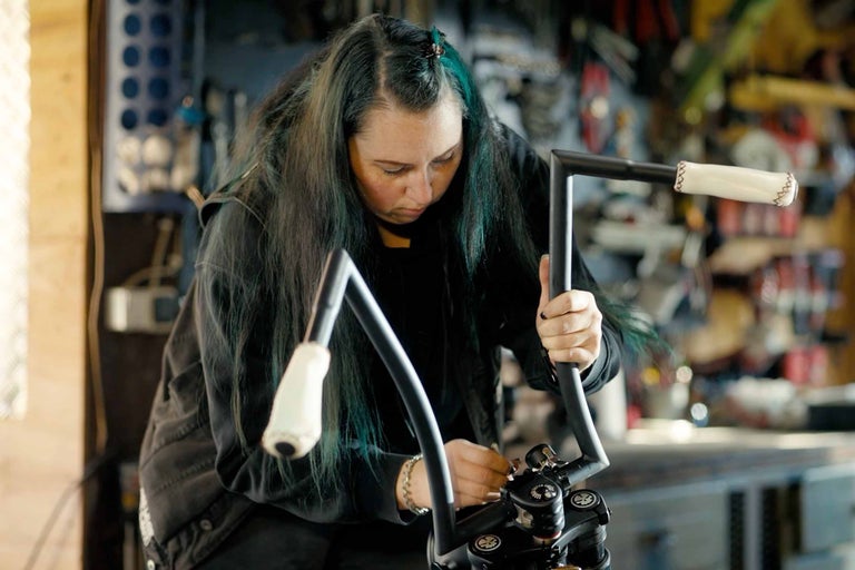 Žena montuje řídítka motocyklu v dílně
