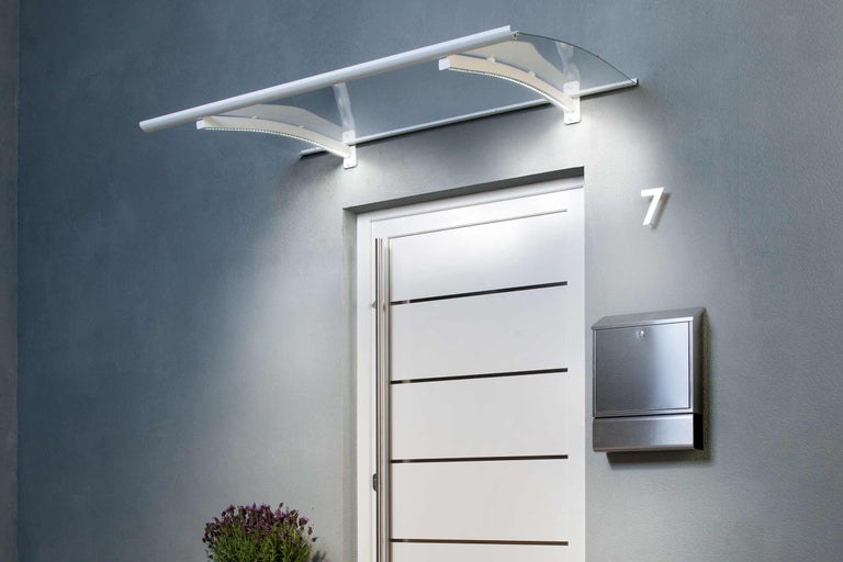 Stříška s osvětlením nad vchodovými dveřmi s poštovní schránkou a číslem domu.