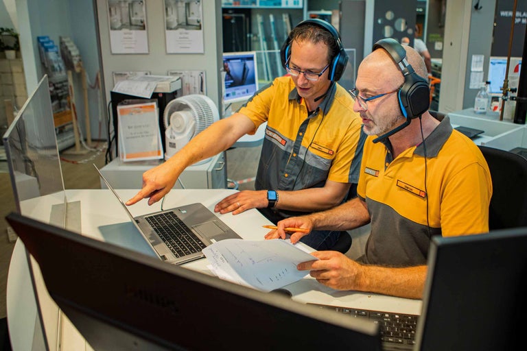 Dva zaměstnanci společnosti Hornbach pracují na notebooku a se stavebními plány.