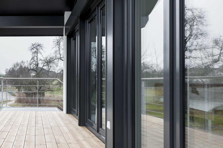 Vícedílný systém posuvných dveří ze skla a hliníku na terase s dřevěnou podlahou