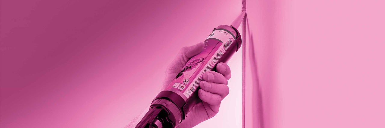 Ruka drží kartuši těsnicí hmoty u rohu.