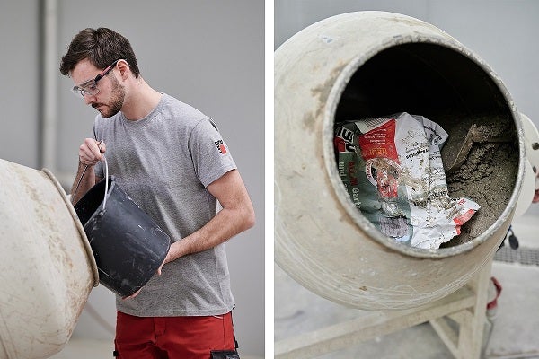 Muž s ochrannými brýlemi lije obsah z kbelíku do míchačky na beton