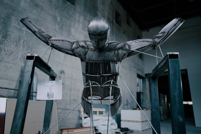 Socha muže z kovových tyčí ve skladu