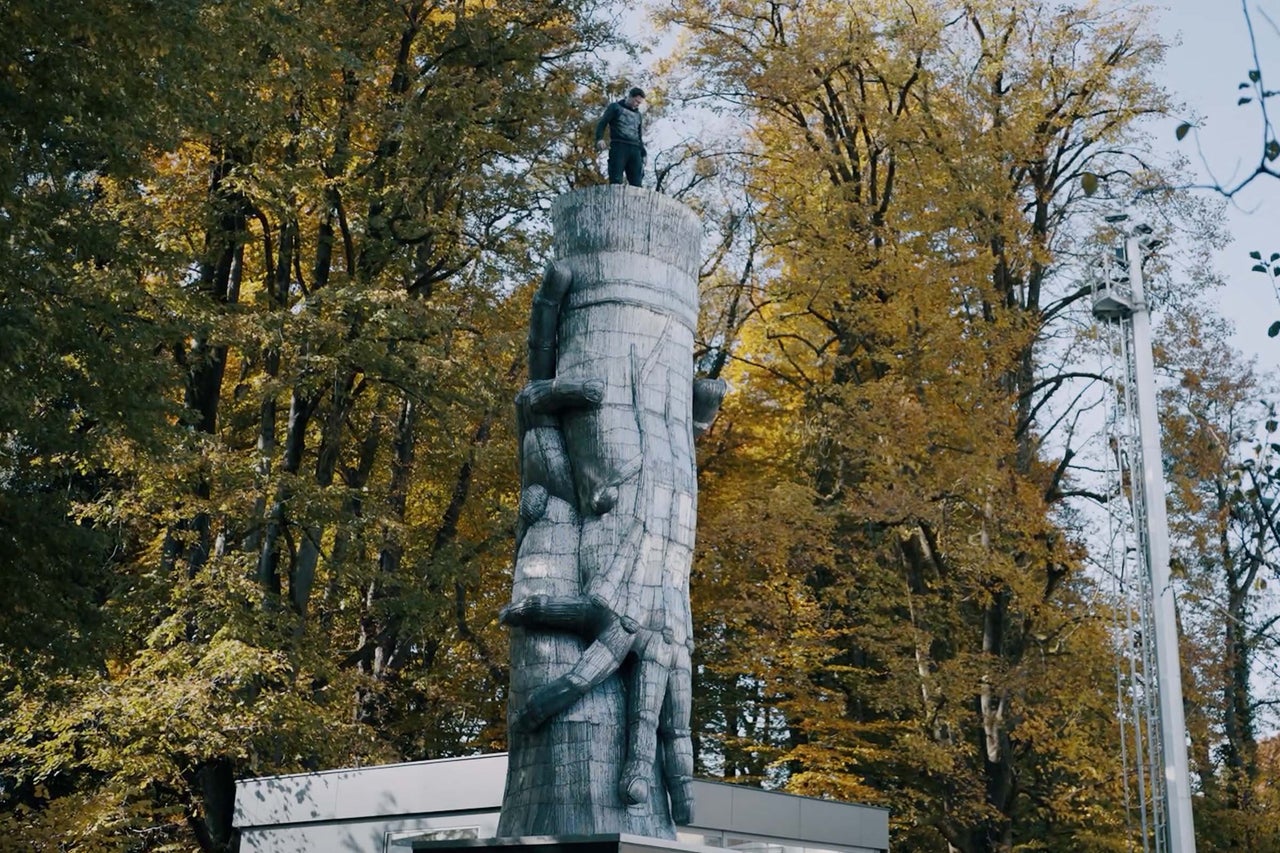 Skulptura skupiny lidí venku, obklopená stromy