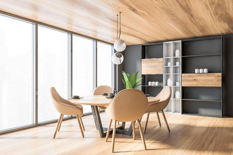 Světlá jídelna s dřevěným stolem, židlemi, regálem a závěsným svítidlem