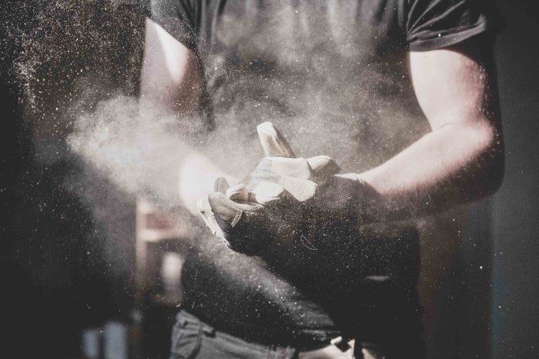 Osoba s pracovními rukavicemi setřásá prach.