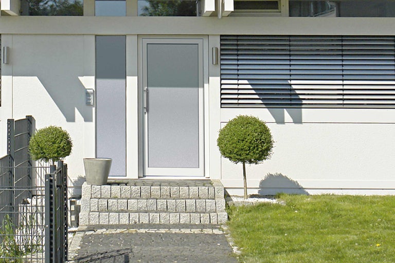 Moderní dům s vchodovými dveřmi, kamennými schody a zahradou
