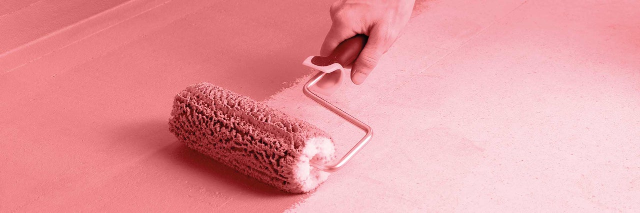 Osoba natírá povrch válečkem na barvu.