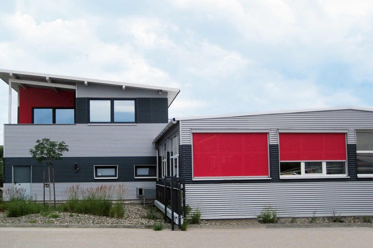 Budova s červeným systémem ochrany proti slunci před okny.