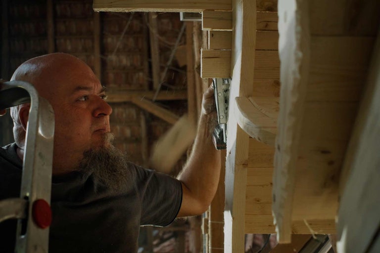 Řemeslník upevňuje dřevěnou konstrukci sponkovačkou