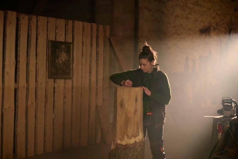 Žena opracovává dřevěný kmen v dílně