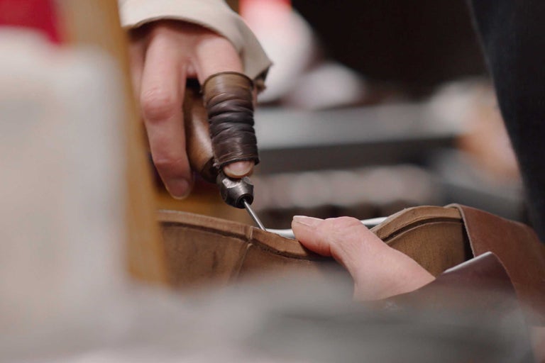 Osoba používá šídlo k šití kůže