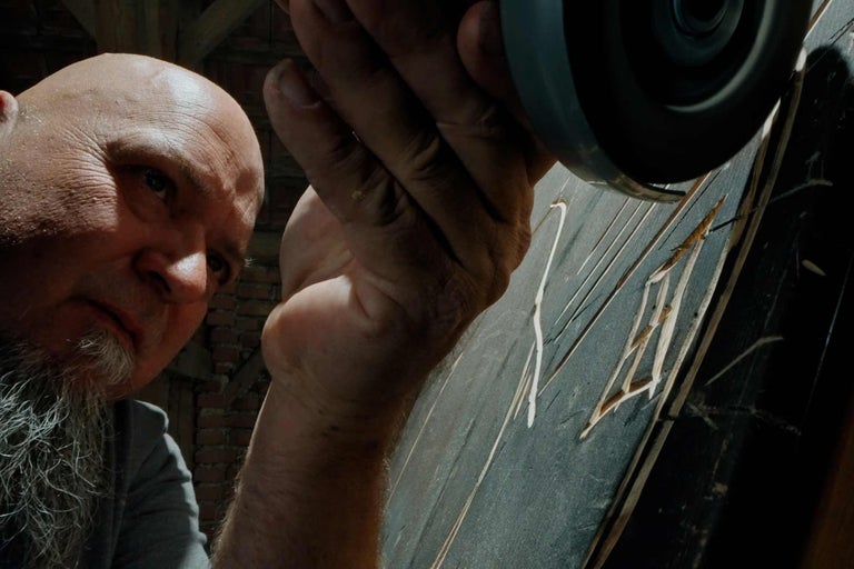 Muž pracuje s úhlovou bruskou na dřevěném obrobku.