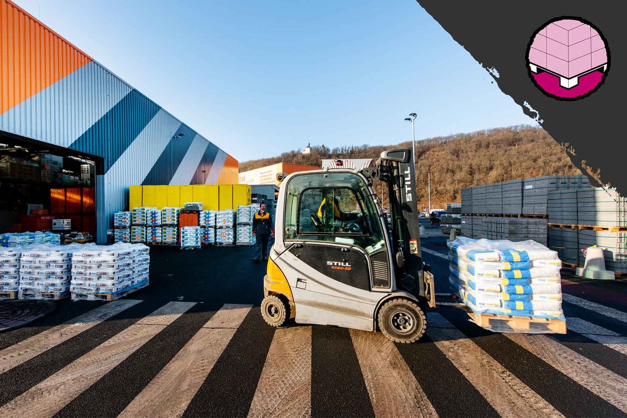 Vysokozdvižný vozík přepravuje palety se stavebními materiály před prodejnou Hornbach.