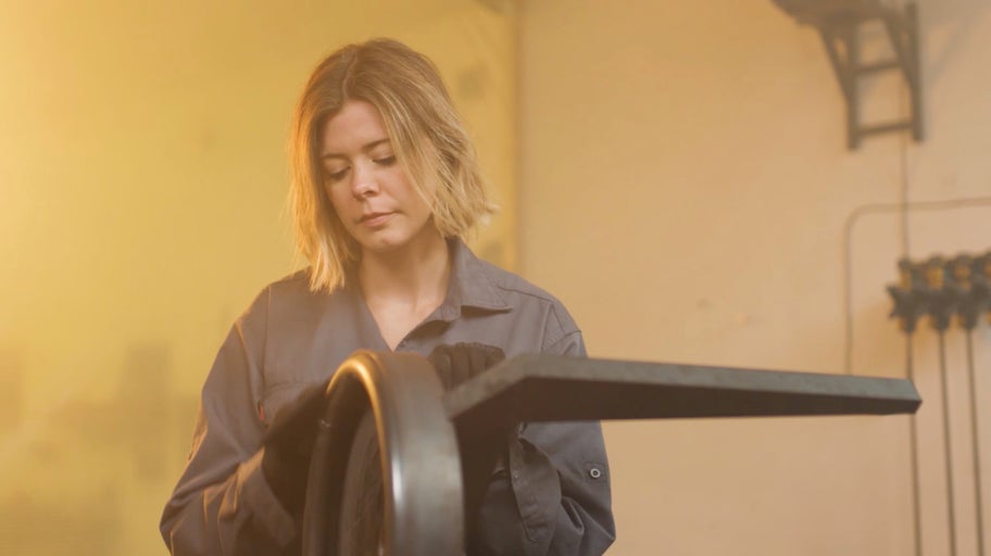 Žena ohýbá kov pomocí ohýbačky.