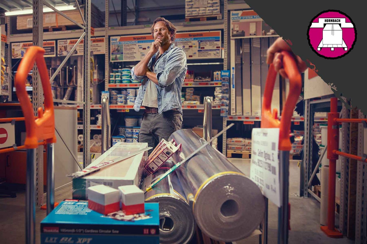 Muž s nákupním vozíkem plným stavebních materiálů v prodejně Hornbach.