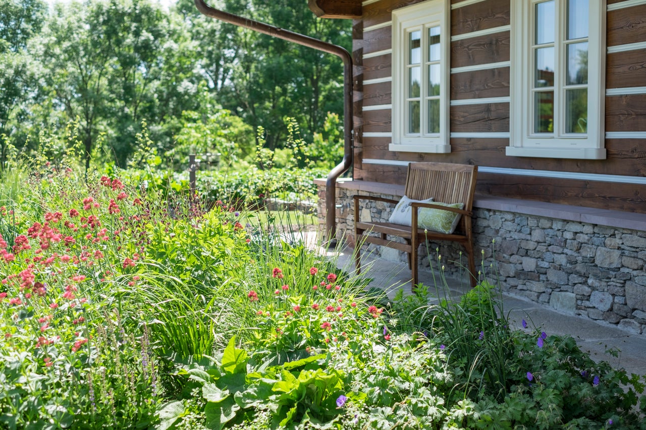 Exteriér dřevěného domu se zahradou a lavičkou