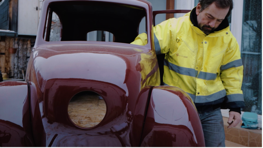 Muž restauruje červené veterán auto.