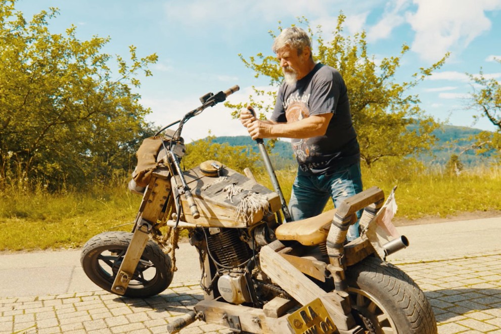
				Willi startuje svoji dřevěnou motorku ručně

			
