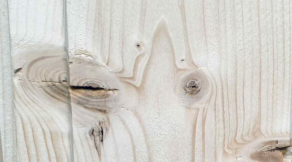 Detail světlého dřevěného povrchu se suky a kresbou